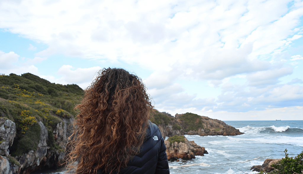 Persona mirando al mar en busca de paz, silencio y calma interior, escuchando las olas para aquietar la mente y silenciar pensamientos intensos.