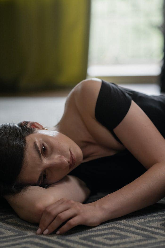 A contemplative woman lying indoors expressing deep emotion and introspection.